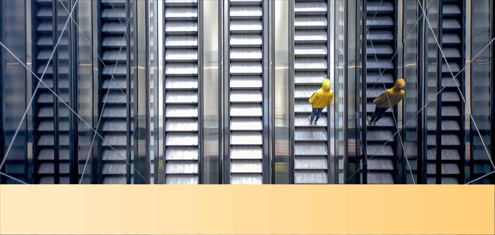 Person in a yellow hooded jacket rides an escalator